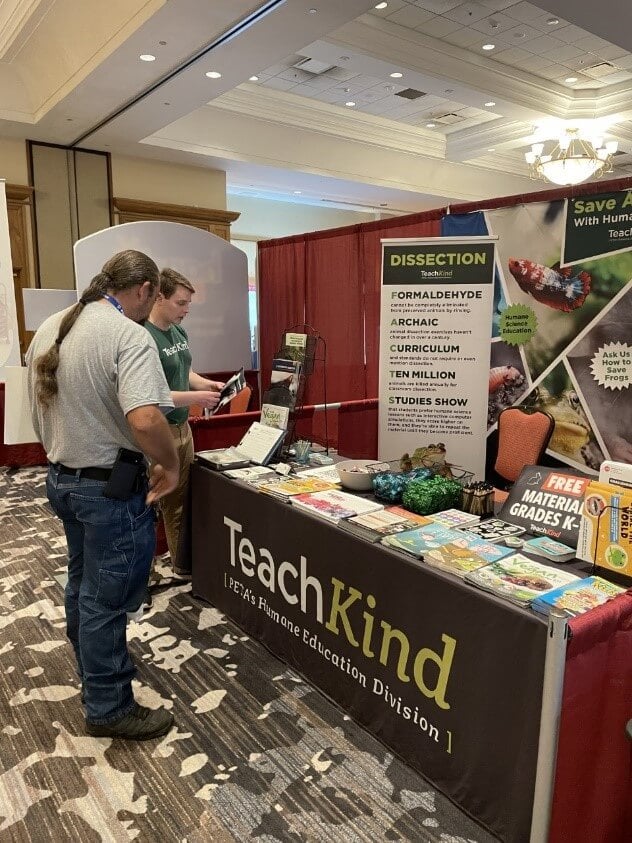 education conference TeachKind exhibit booth at FAST with staffer talking to a teacher