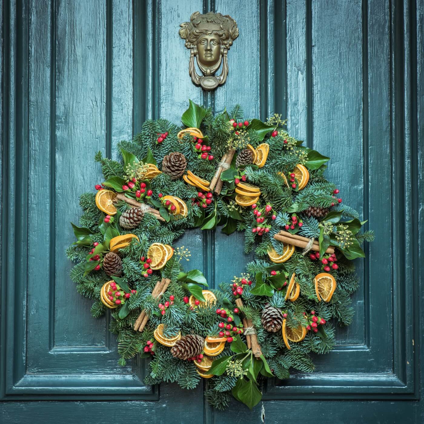 evergreen and dried orange yule wreath hanging on a door