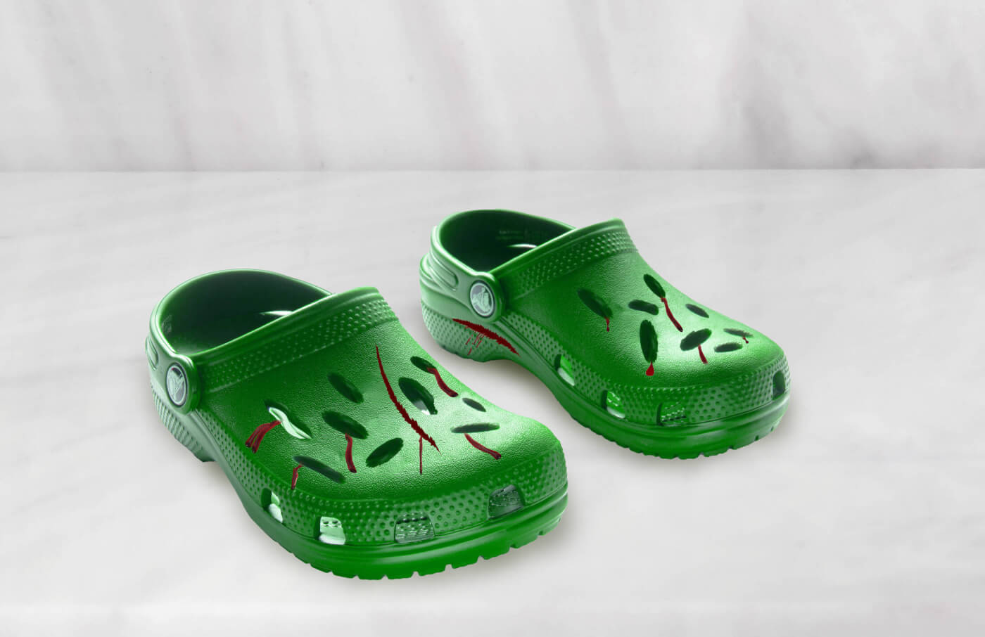 a pair of green crocs that appear to be covered in cuts and fake blood as part of the Cruelty Rebranded campaign