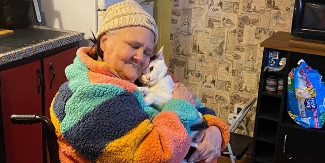 cat cuddling with CAP client in colorful sweater