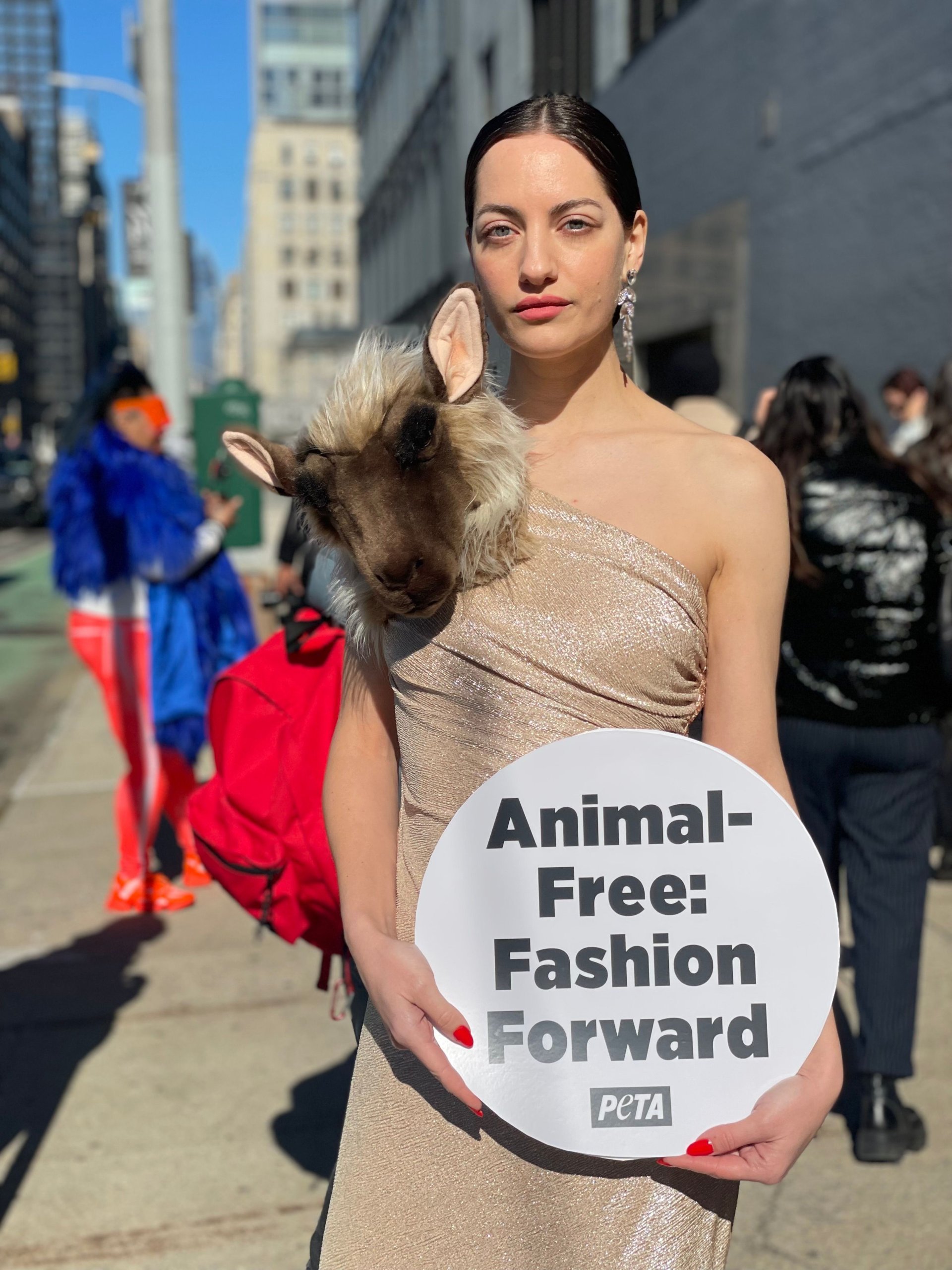 NY Fashion Week PETA model wearing Schiaparelli-esque faux sheep dress and holding sign saying "Animal Free: Fashion Forward"