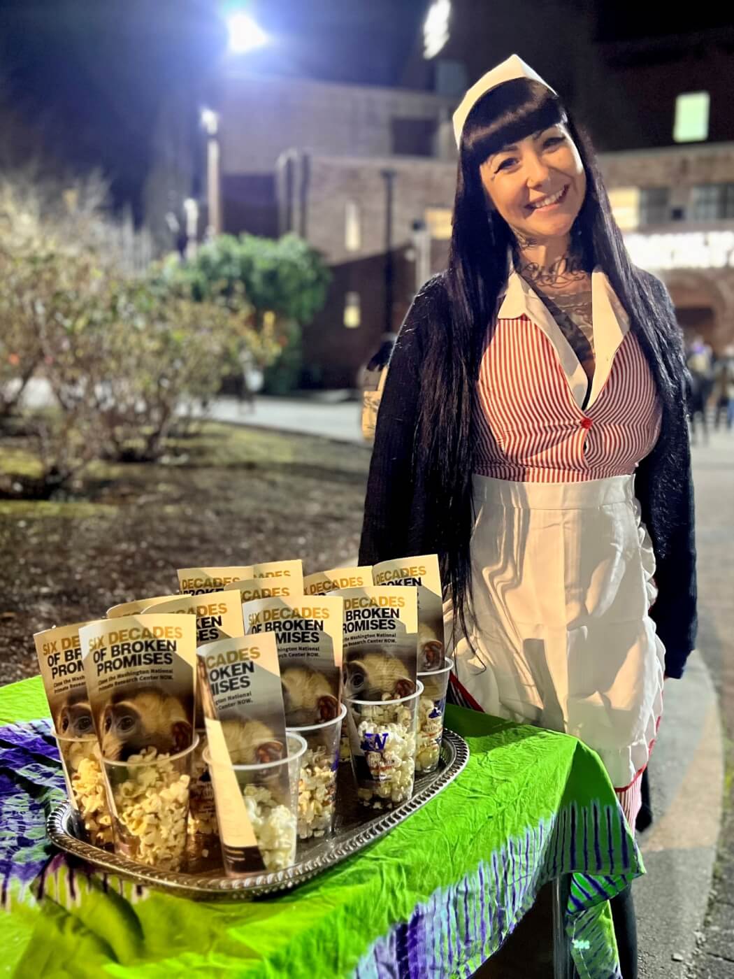 PETA staffer stands next to a table of cups with popcorn and flyers