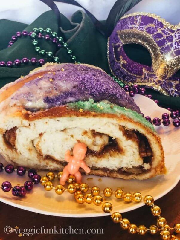 vegan mardi gras king cake with decorations and a little plastic baby
