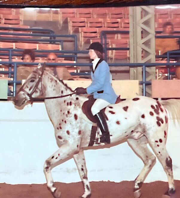 Kathy Guillermo riding a spotted horse in traditional polo gear