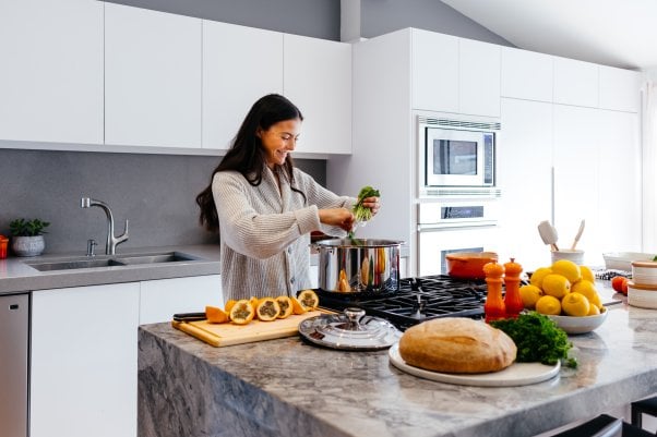 happy woman cooking with veggies and fruit in a modern kitchen