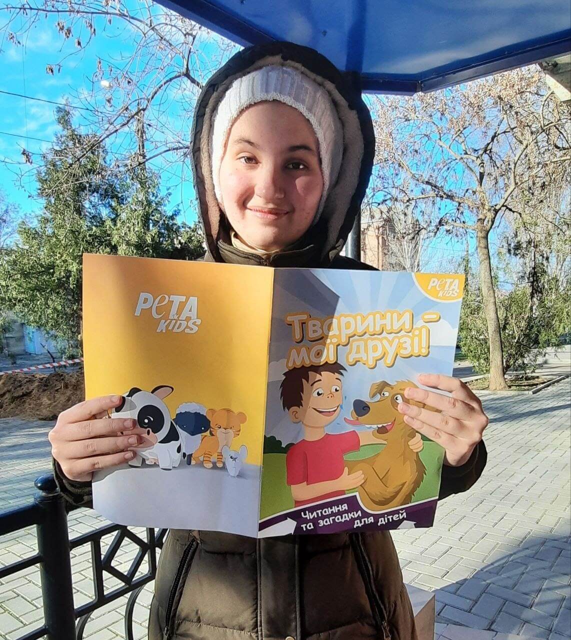 A child in Ukraine poses with a PETA Kids brochure