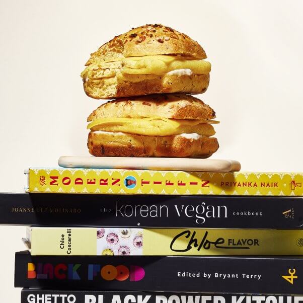 two of the barnes & noble cafe vegan breakfast sandwiches staked on top of each other sitting atop several vegan cookbooks