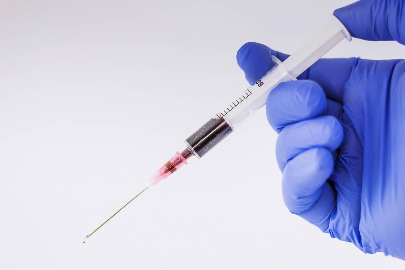 Photo of a gloved hand holding a syringe