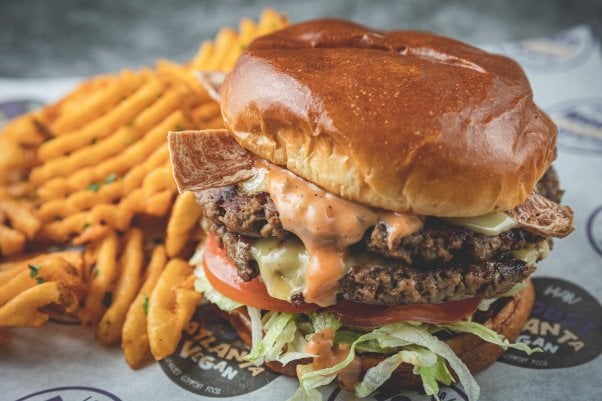 double patty WAP-er burger from Houstatlantavegan, with vegan bacon and a side of waffle cut fries in the background