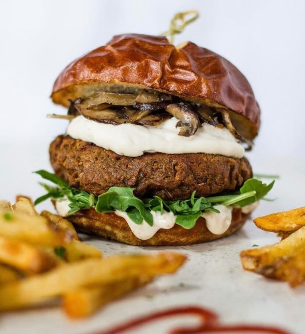 close photo of a vegan Mushroom Swizz burger from Modern Love, with fries out of focus in the foreground