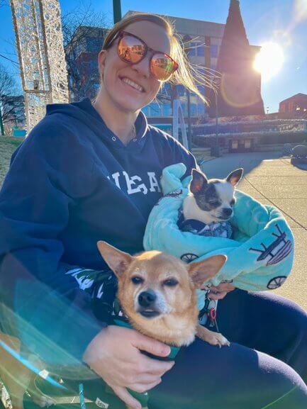 two happy dogs pose with a human in the sunshine