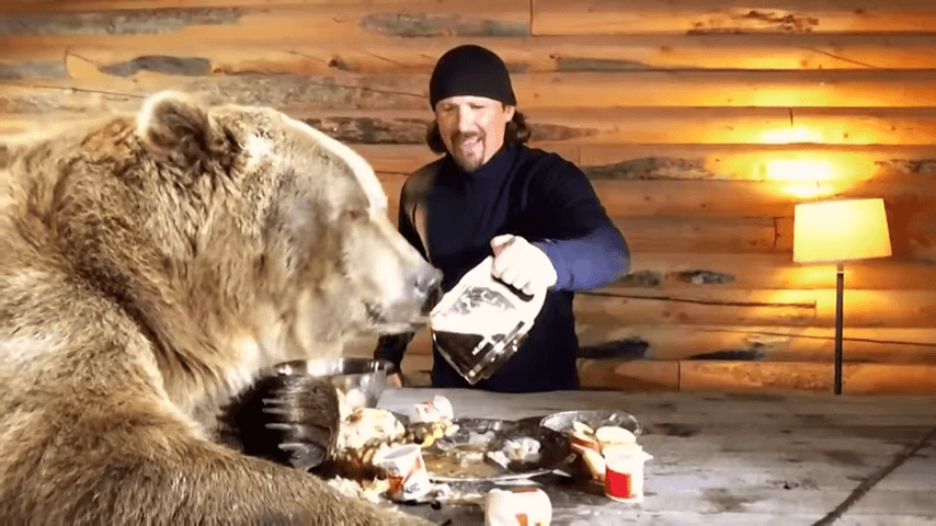 men feeding a grizzly bear a pot of coffee
