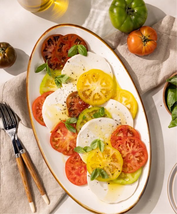 Fresh Mozzarella from Miyoko's on a plate with basil and tomato and olive oil.