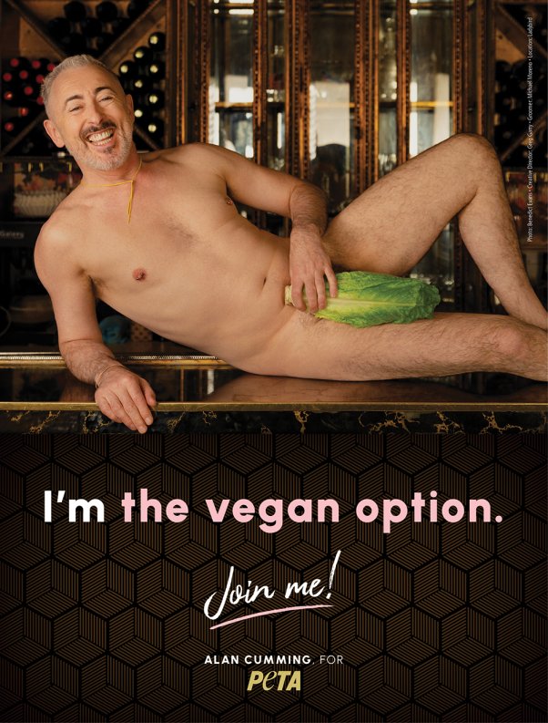 Alan Cumming poses on bar with lettuce leaf covering lower half