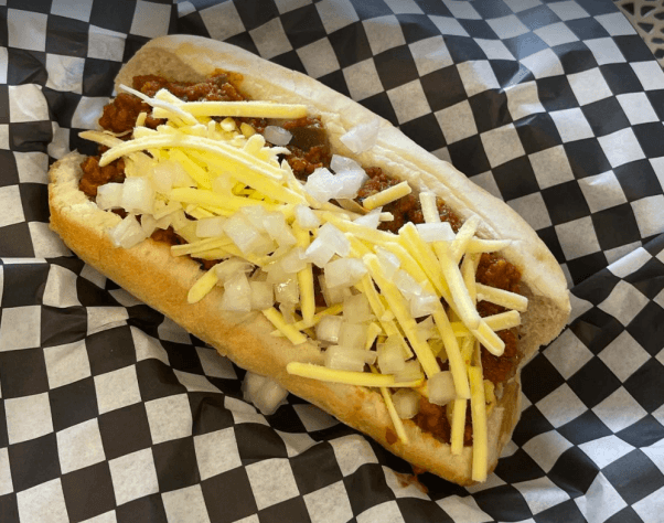 vegan chili dog topped with onions and cheese