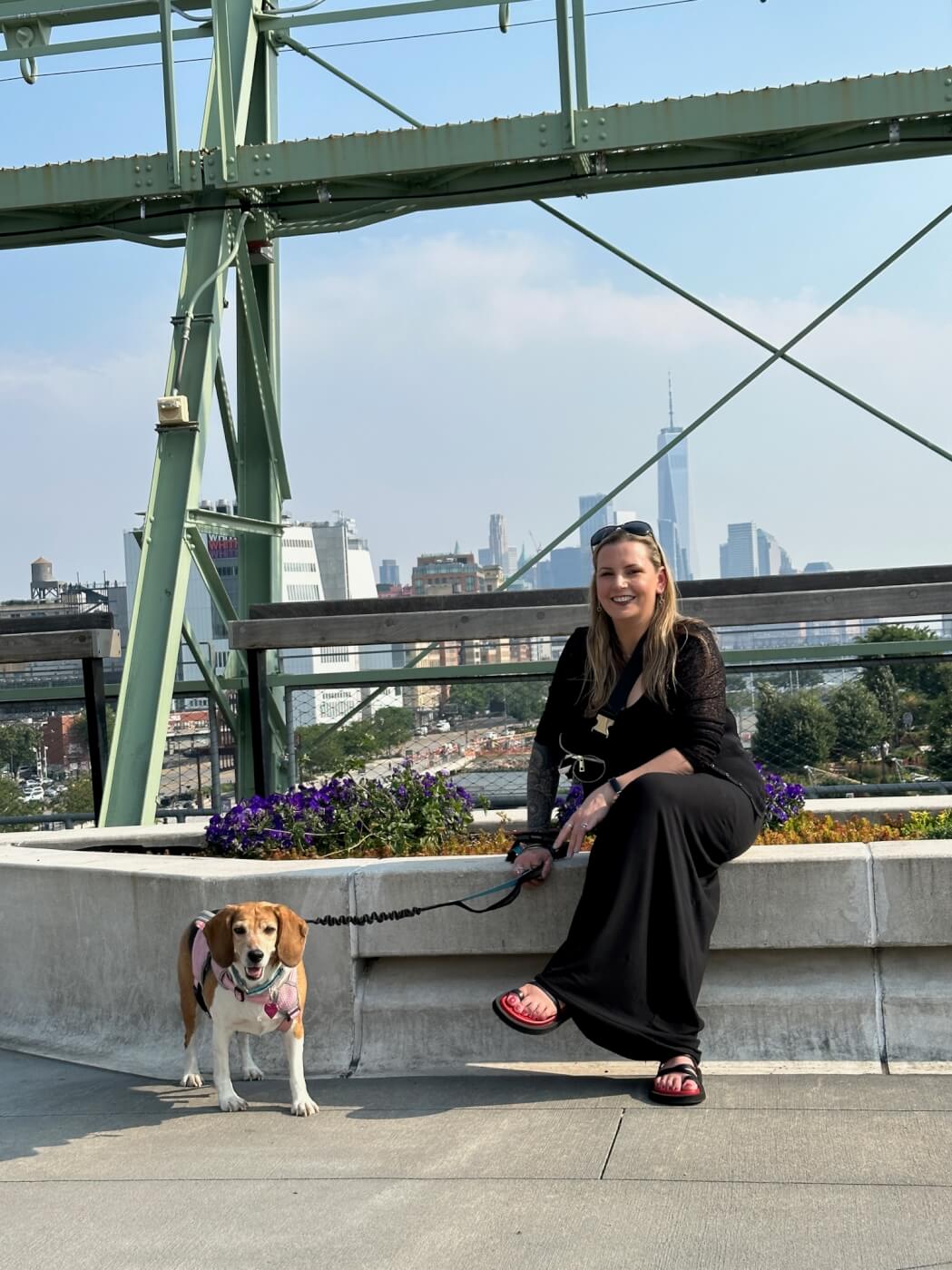 woman on a walk with her companion beagle in front of city scenery
