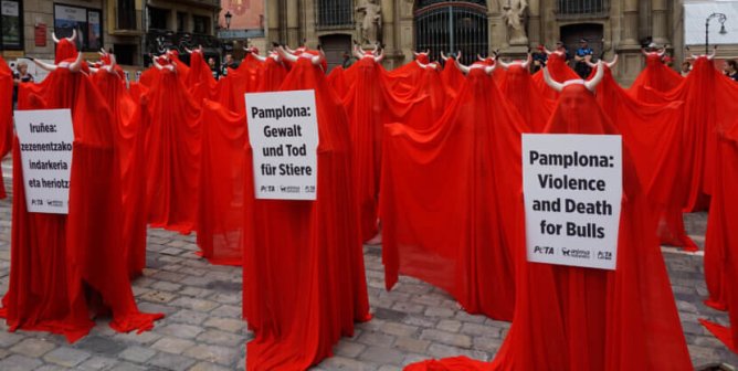 Group of protesters dressed in red cloaks against bullfighting