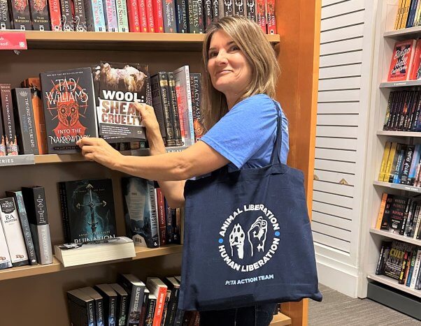 Keli places PETA Literature items inside books at a library