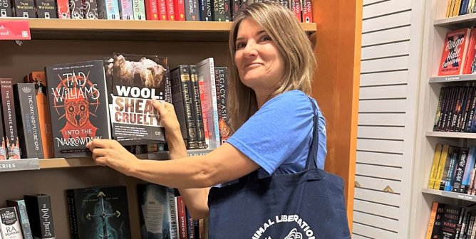 Keli places PETA Literature items inside books at a library