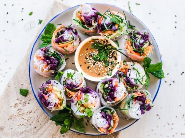 plate of fresh spring rolls with a bowl of peanut sauce in the middle