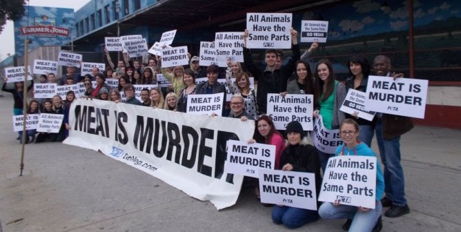 animal advocates doing a protest with signs and a large banner that reads "MEAT IS MURDER", to help make a Farmer John slaughterhouse shut down