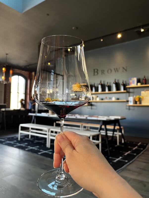 hand holding a glass of red wine at brown winery in napa, california