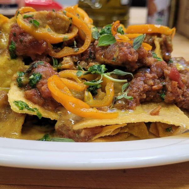 closeup photo of vegan nachos with jackfruit meat and peppers