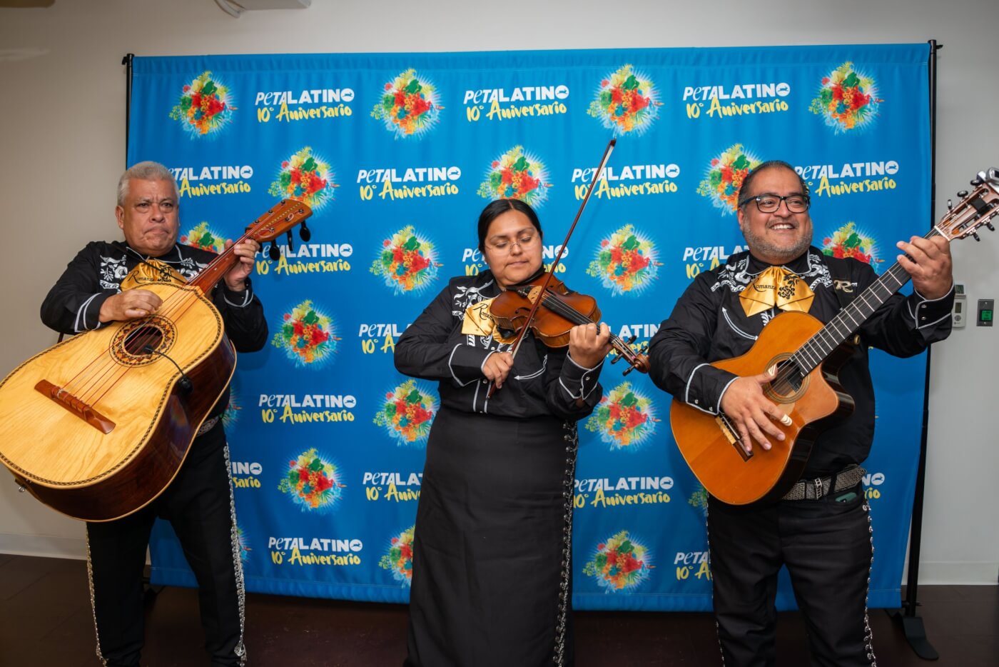 Rodrigo Rodriguez Diaz and his Mariachi Romanza playing instruments in front of PETA Latino's tenth anniversary banner