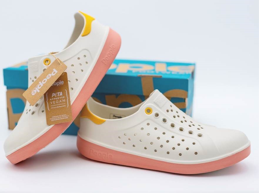White shoe with pink soles. There is a People PETA approved tag attached to it