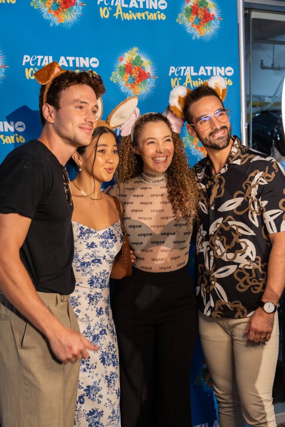 four attendees of the PETA Latino tenth anniversary party, in front of the celebratory banner
