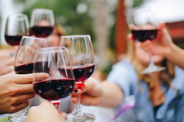 a group of people holding glasses of red wine