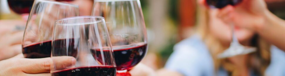 a group of people holding glasses of red wine