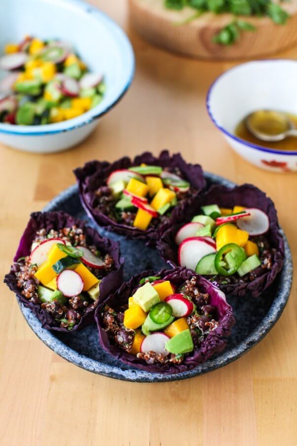 a plate with red cabbage cups filled with quinoa and vegetables