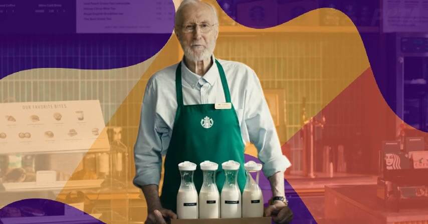 James Cromwell with vegan milk dressed in starbucks uniform with swirling colors