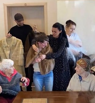 teams supported by PETA donating fur coats to Ukraine, showing one person trying on a coat with others watching