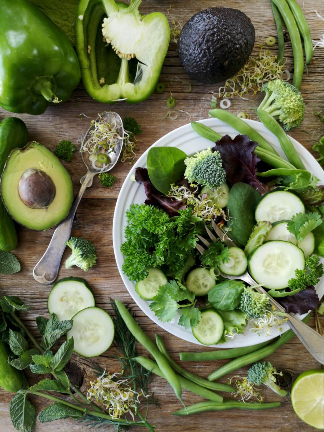 plate of green foods including cucumber, avocado, and leafy greens that are vegan and can help curb constipation