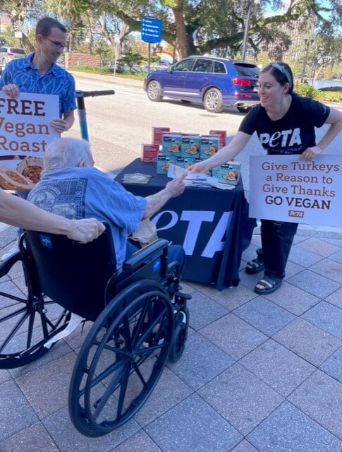 PETA supporters hand out a vegan roast to a person in a wheelchair
