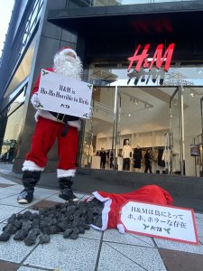 In front of an H&M store. One person dressed as Santa holding a sign reading
