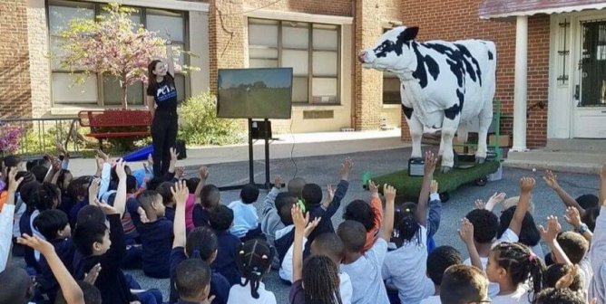 Ellie elephant TeachKind tour children raising hands