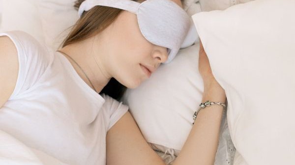 woman sleeping in a bed with an eye mask on