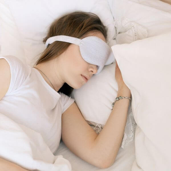 woman sleeping in a bed with an eye mask on