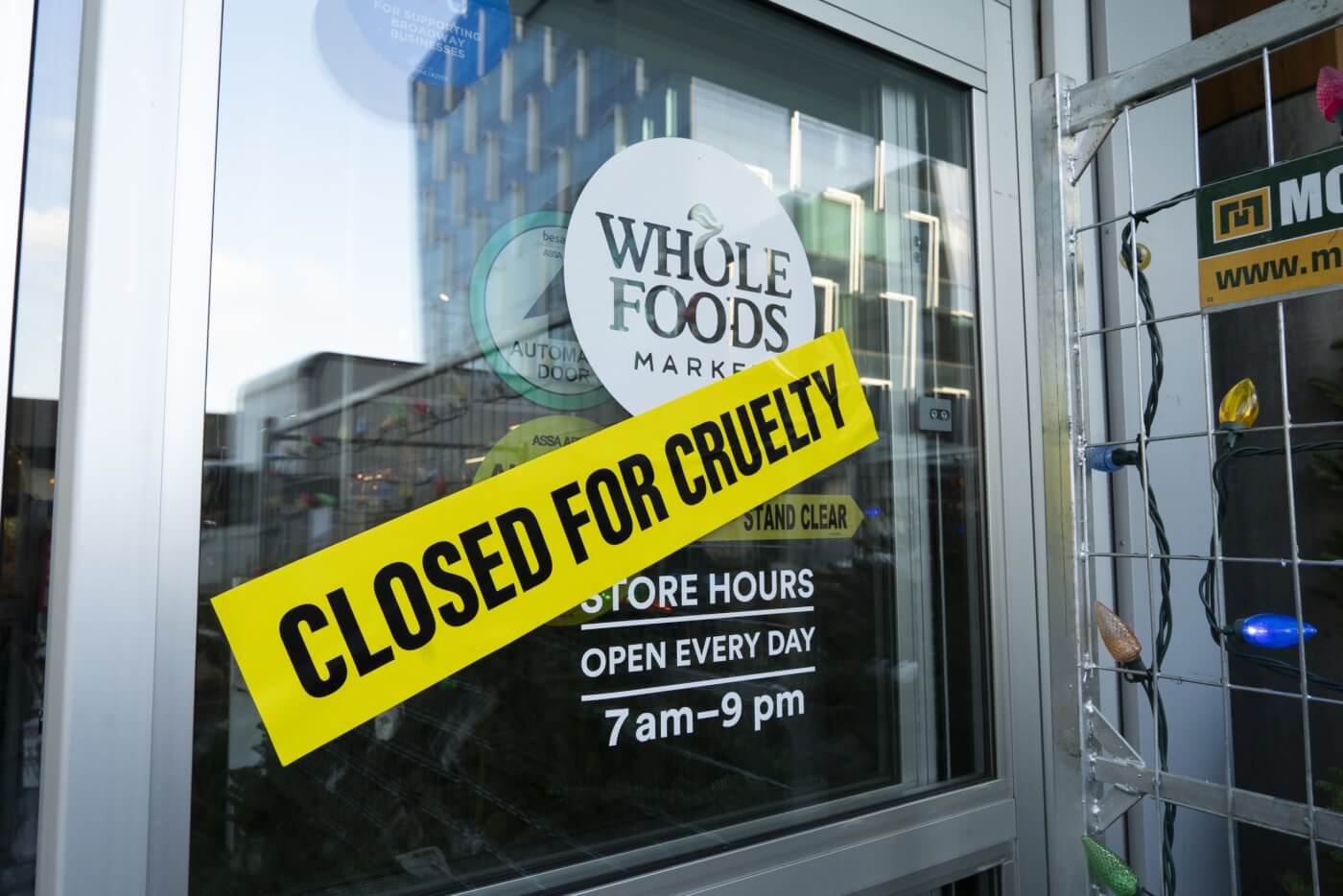 a "Closed for Cruelty" sign stretched across a Whole Foods store window in Vancouver, as part of a peaceful PETA demonstration protesting coconut milk from Thailand