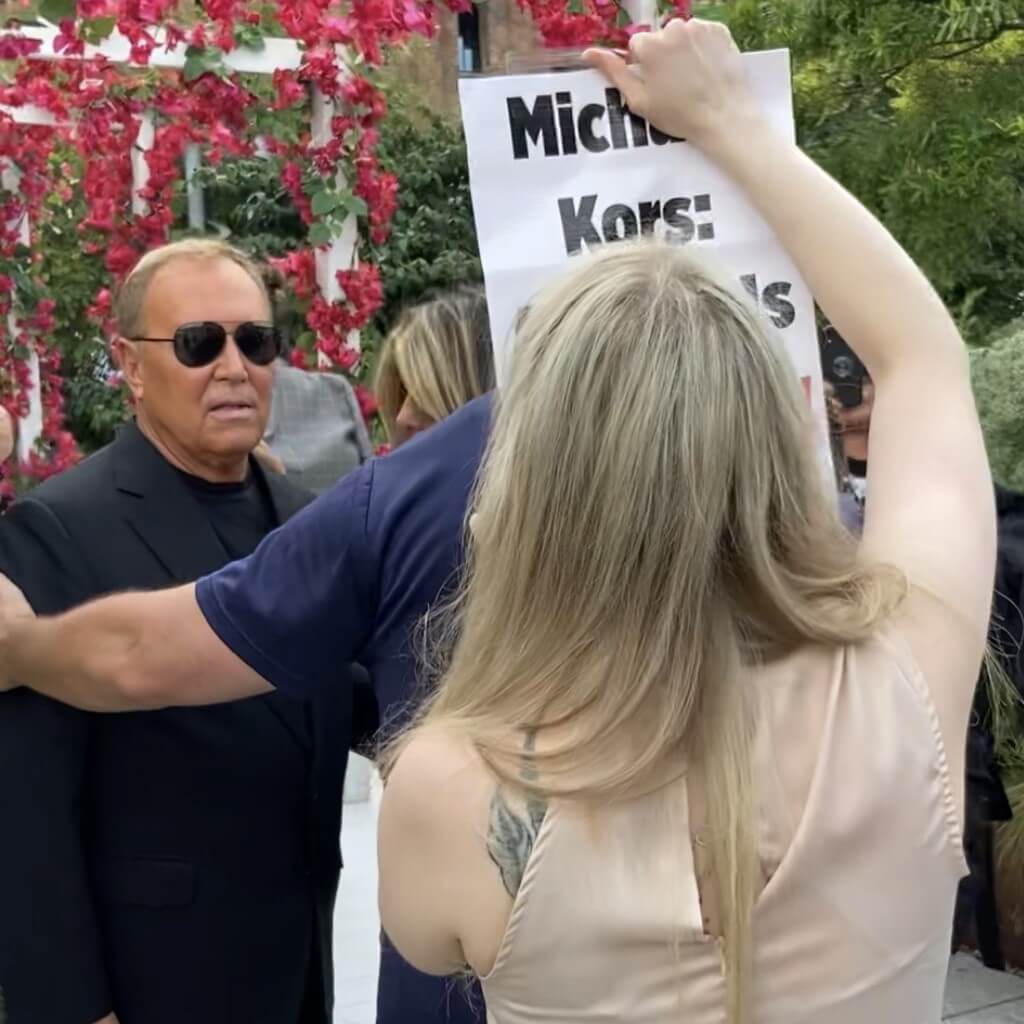 A PETA protester holds a sign in front of Michael Kors
