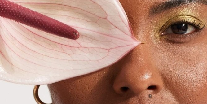 Black-owned brand the honey pot's image showing person with makeup on with a flower in front of their eye