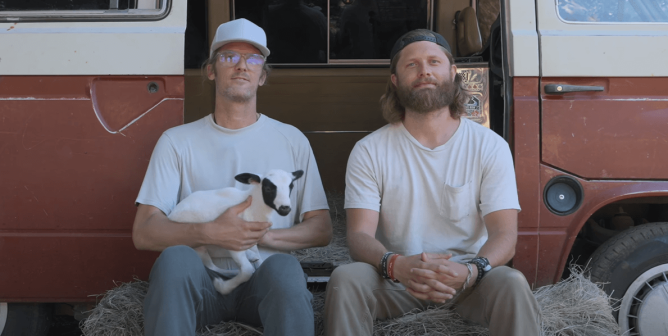 The directors from Christpiracy sit on a hale bale in front of a van. One holds a lamb.