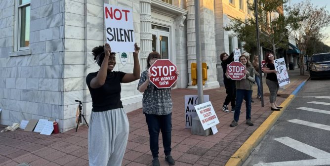 Demonstrators holding signs stand outside of Bainbridge City Hall