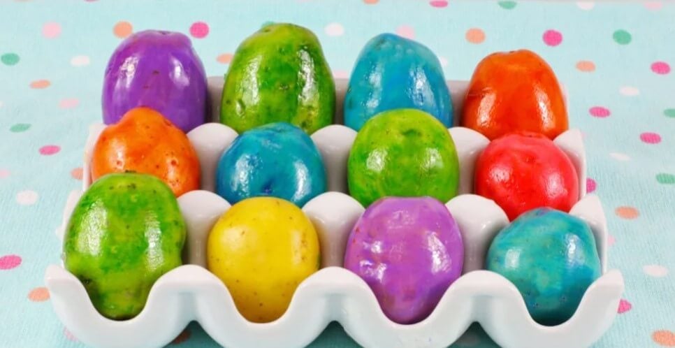 a variety of colorful dyed potatoes, similar to Easter eggs, displayed in a white tray