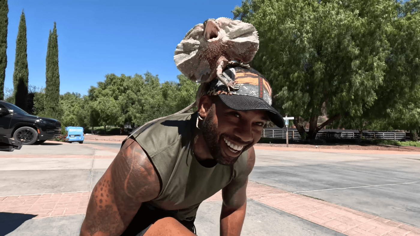 man placing lizard on top of his head