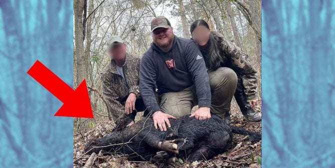 Will Moseley posing with a dead pig with two other hunters, whose faces are blurred