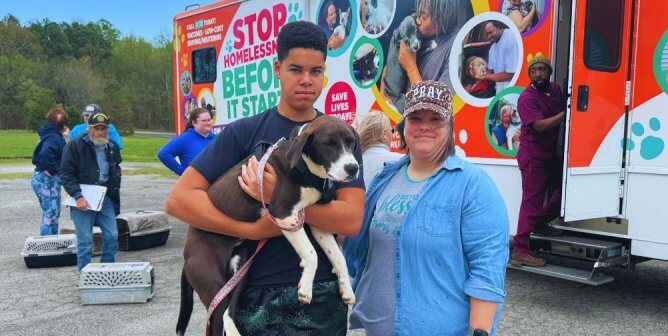 Two people holding their dog at PETA's Spay neuter event